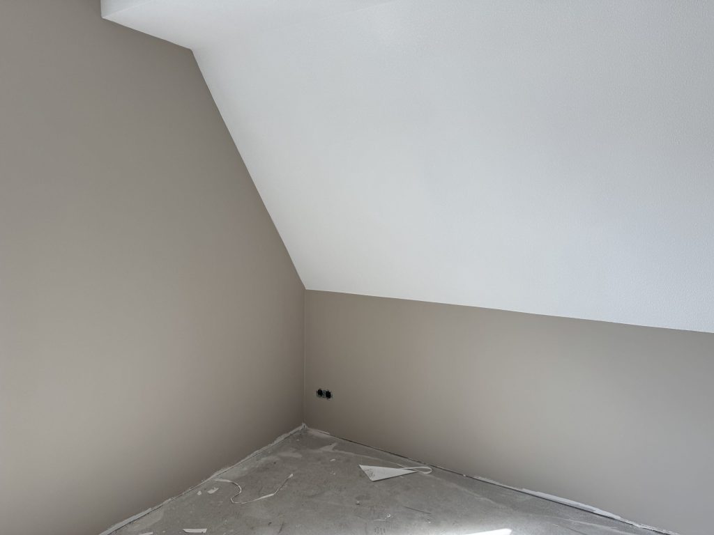 Zolderkamer met een schuine wand, afgewerkt in wit en zandkleur